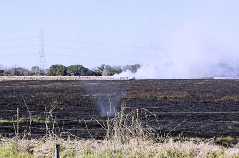 A dust devil forms on a scorched hay meadow at the Dopslauph Farm in Mullins Prairie while a grass fire burns in the background.